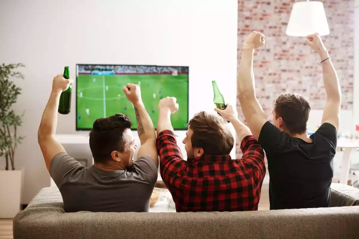 Tres hombres viendo un partido de fútbol en la televisión