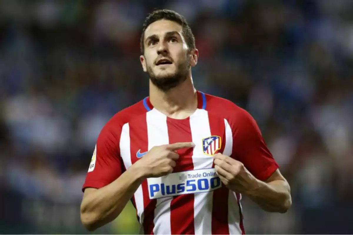 Koke con la camiseta del Atlético de Madrid señalando el escudo del equipo.