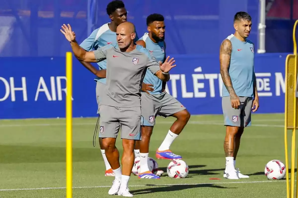 Entrenador y jugadores del Atlético de Madrid en una sesión de entrenamiento en el campo de fútbol.