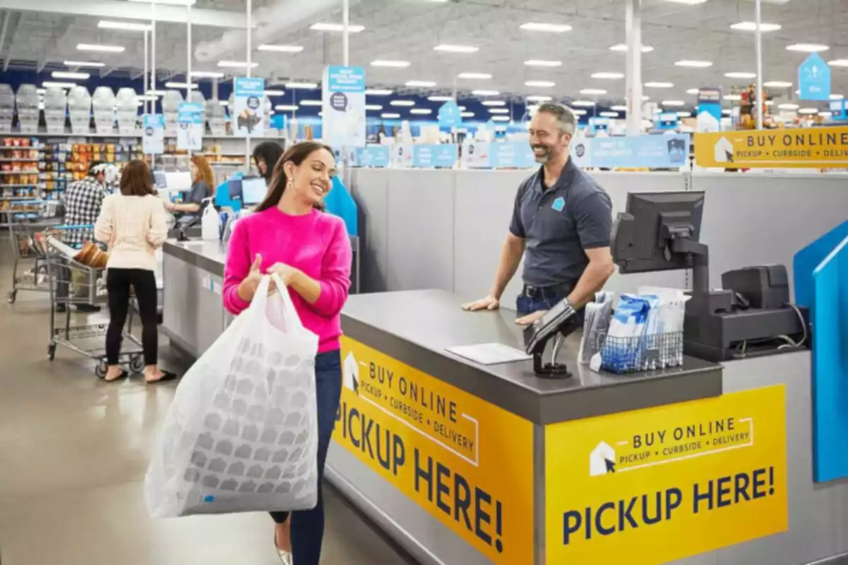 Mujer sonriente recoge una bolsa grande en el área de recolección de compras en una tienda mientras un empleado la atiende y otras personas hacen fila al fondo Mujer sonriente recoge una bolsa grande en el área de recolección de compras en una tienda mientras un empleado la atiende y otras personas hacen fila al fondo