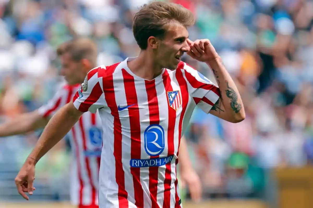 Futbolista del Atlético de Madrid celebrando un gol en el campo con la camiseta rojiblanca y fondo de aficionados desenfocados Futbolista del Atlético de Madrid celebrando un gol en el campo con la camiseta rojiblanca y fondo de aficionados desenfocados
