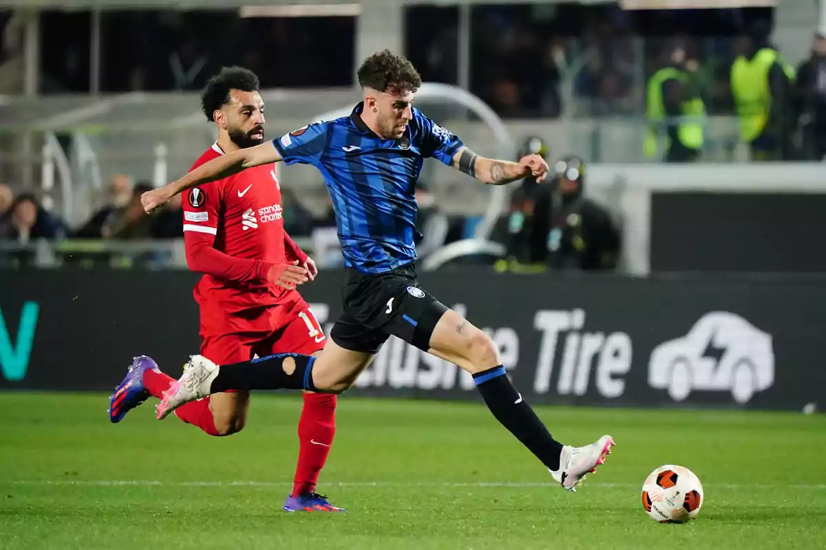 Dos futbolistas disputan el balón durante un partido en un estadio lleno de espectadores Dos futbolistas disputan el balón durante un partido en un estadio lleno de espectadores