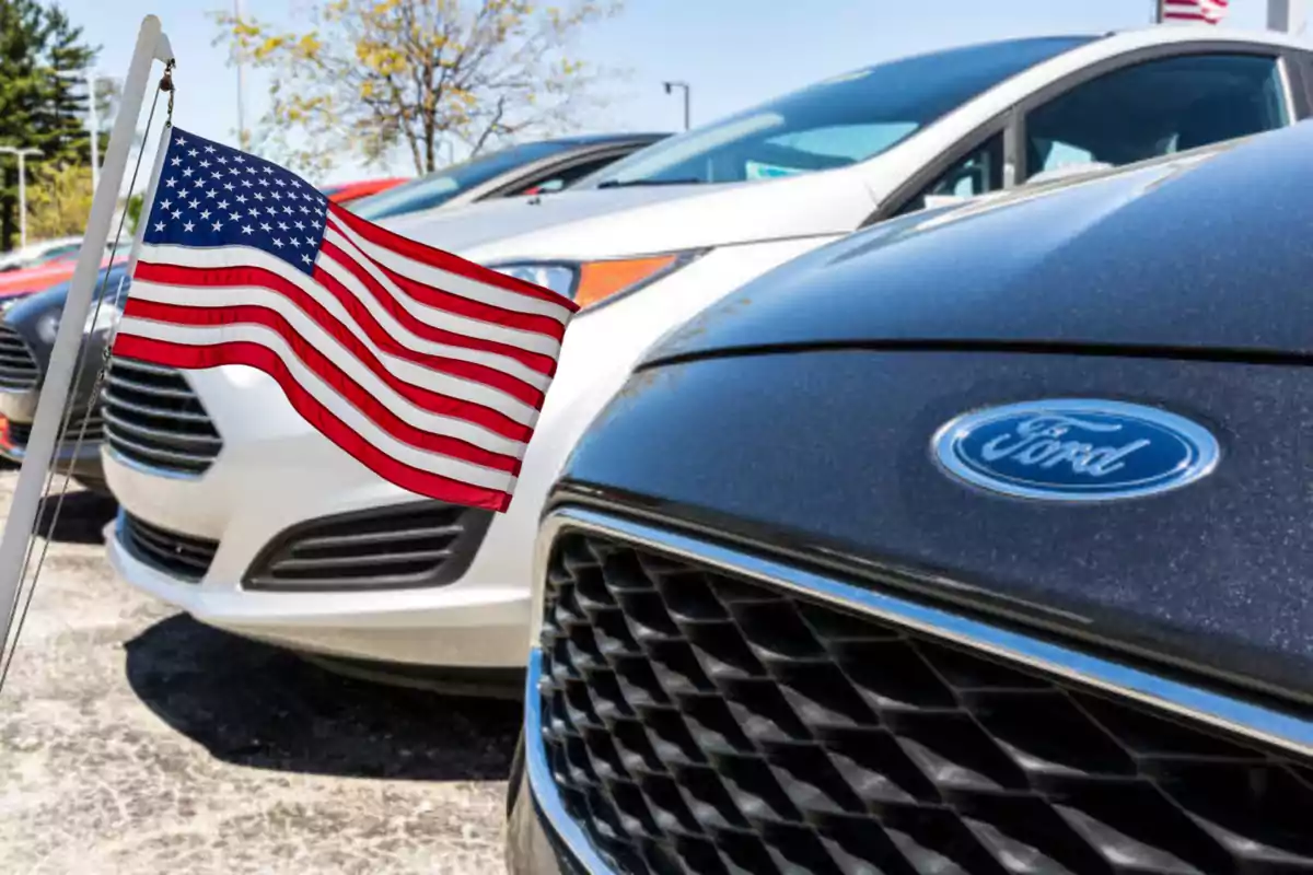 Autos Ford estacionados junto a una bandera de Estados Unidos ondeando Autos Ford estacionados junto a una bandera de Estados Unidos ondeando