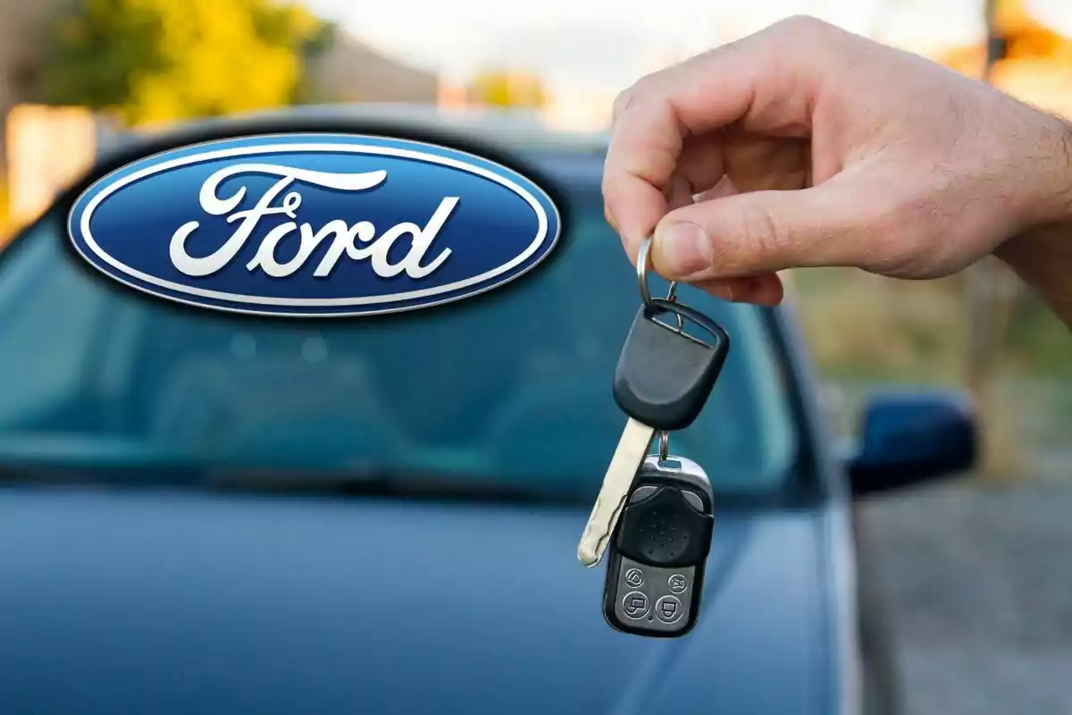 A hand holds car keys in front of a vehicle with the Ford logo in the foreground.