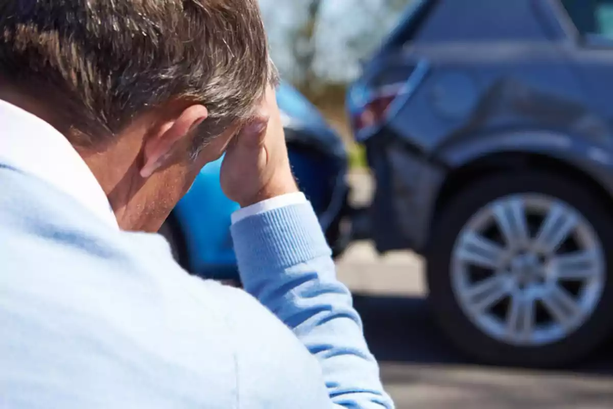 Worried man holds his head while looking at a car accident. Worried man holds his head while looking at a car accident.