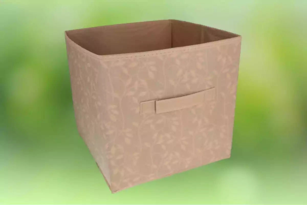 Caja organizadora de tela color beige con diseño de hojas y asa al frente sobre fondo verde difuminado Caja organizadora de tela color beige con diseño de hojas y asa al frente sobre fondo verde difuminado