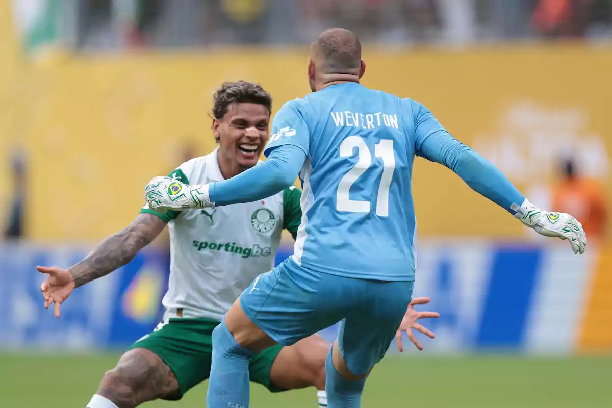 Dos jugadores de fútbol del Palmeiras celebran efusivamente en el campo uno de ellos lleva uniforme de portero azul y el otro viste de blanco y verde Dos jugadores de fútbol del Palmeiras celebran efusivamente en el campo uno de ellos lleva uniforme de portero azul y el otro viste de blanco y verde