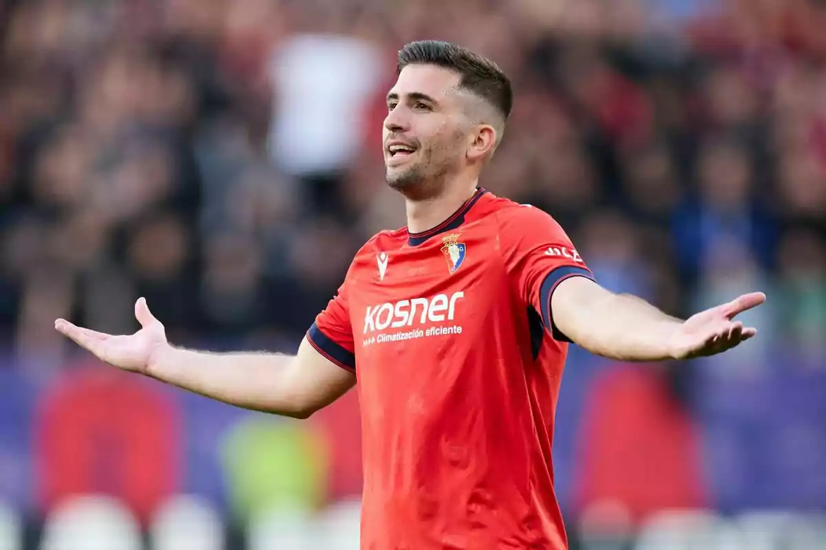 Futbolista con uniforme rojo de Osasuna gesticulando con los brazos abiertos durante un partido Futbolista con uniforme rojo de Osasuna gesticulando con los brazos abiertos durante un partido