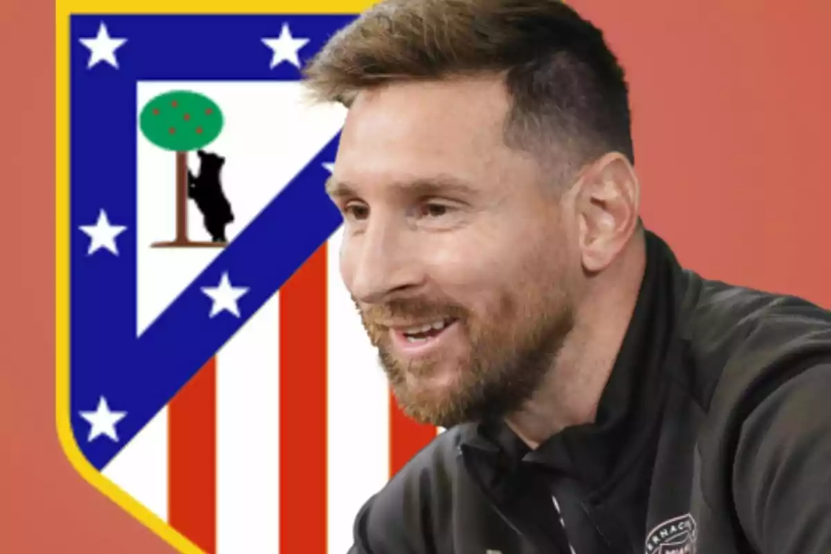 Un hombre sonriente en primer plano con el escudo del Atlético de Madrid de fondo