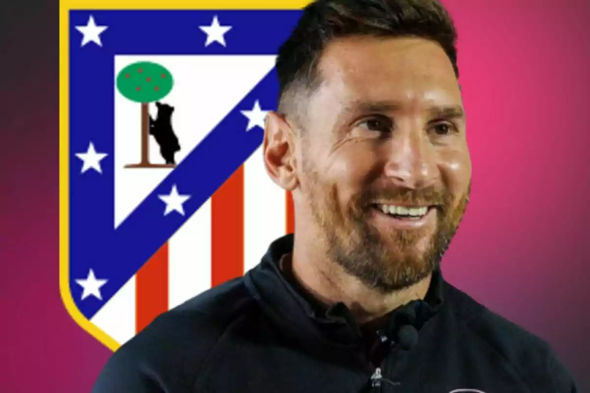 Un hombre sonriente con barba frente al escudo del Atlético de Madrid