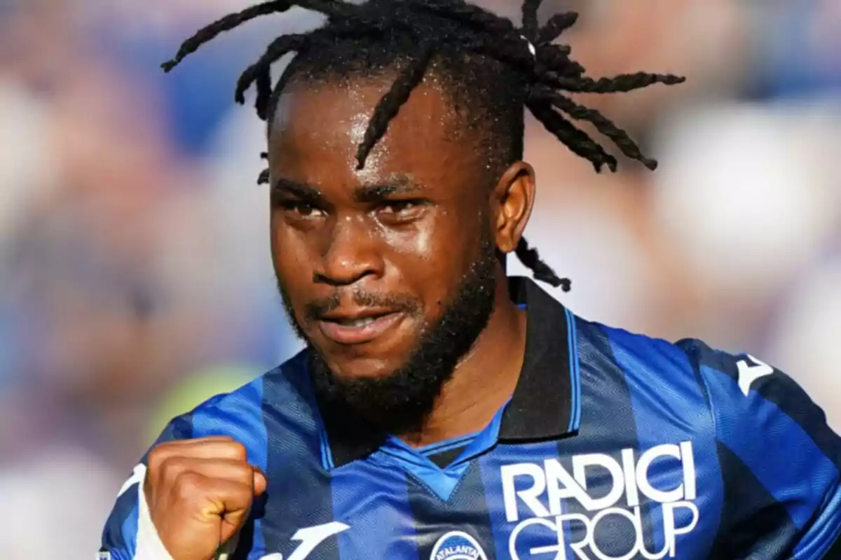 Futbolista con camiseta azul y negra celebrando con el puño cerrado y expresión de determinación en el rostro Futbolista con camiseta azul y negra celebrando con el puño cerrado y expresión de determinación en el rostro