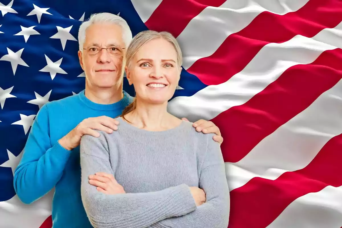 Pareja de personas mayores sonriendo frente a una bandera de Estados Unidos