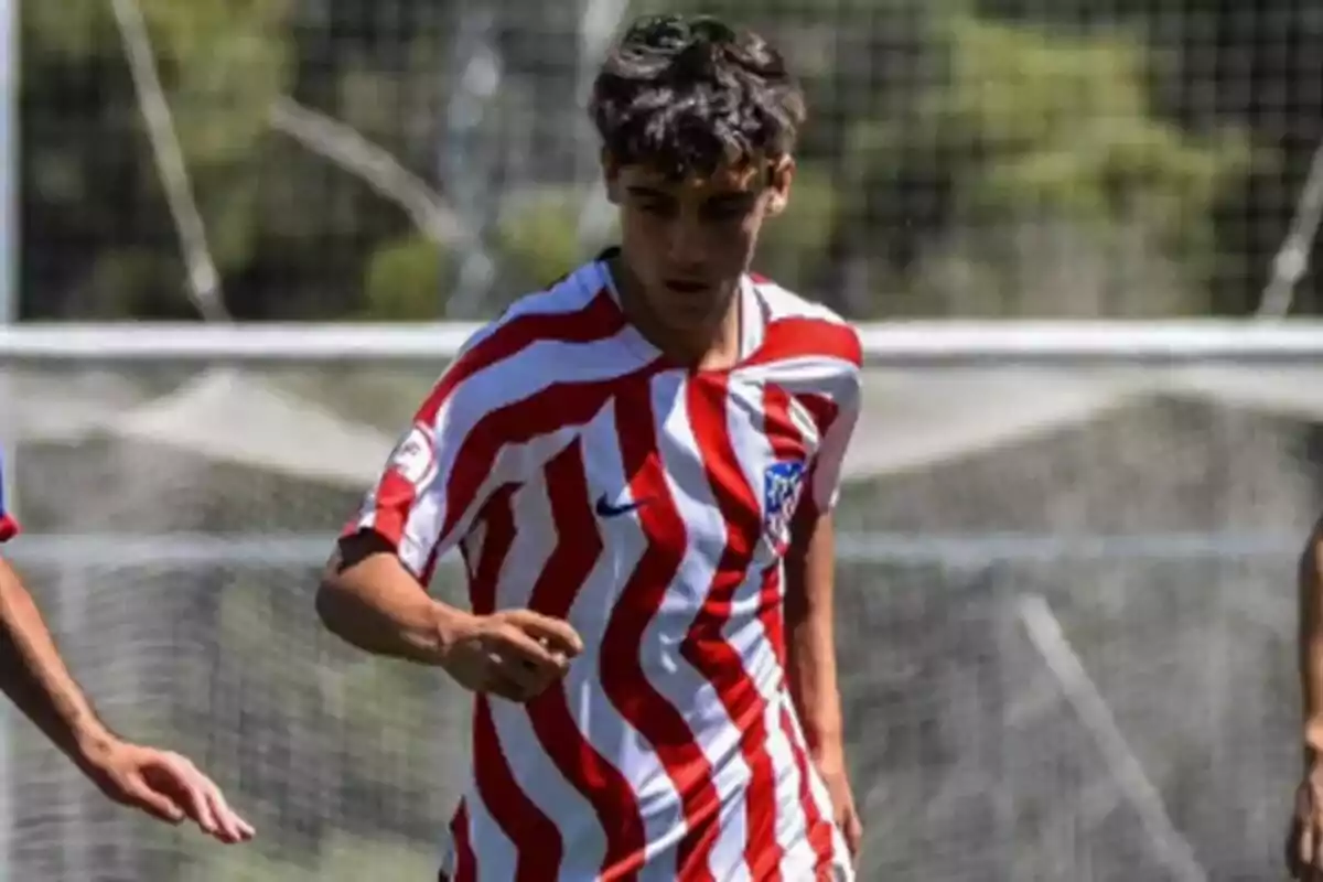 Joven futbolista con camiseta de rayas rojas y blancas jugando en un campo de fútbol Joven futbolista con camiseta de rayas rojas y blancas jugando en un campo de fútbol