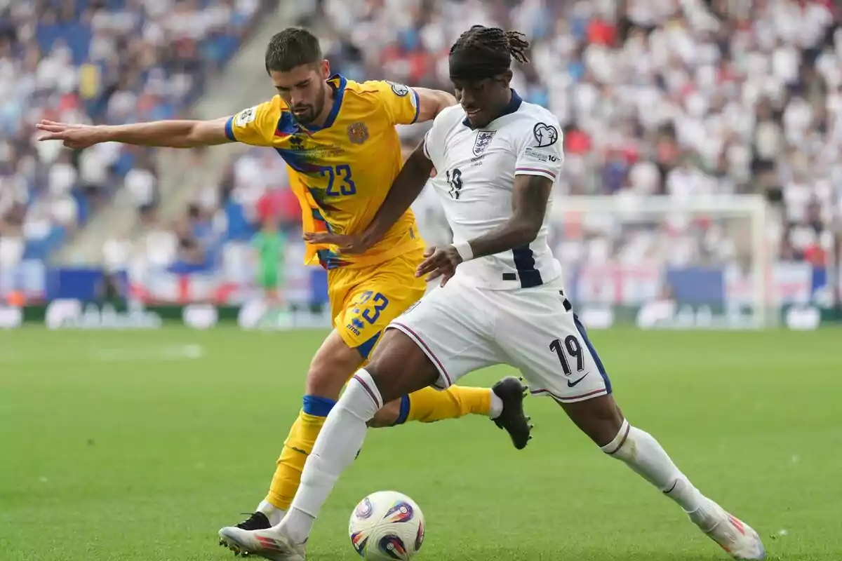 Dos futbolistas disputan el balón durante un partido, uno con uniforme amarillo y el otro con uniforme blanco, en un estadio lleno de espectadores. Dos futbolistas disputan el balón durante un partido, uno con uniforme amarillo y el otro con uniforme blanco, en un estadio lleno de espectadores.