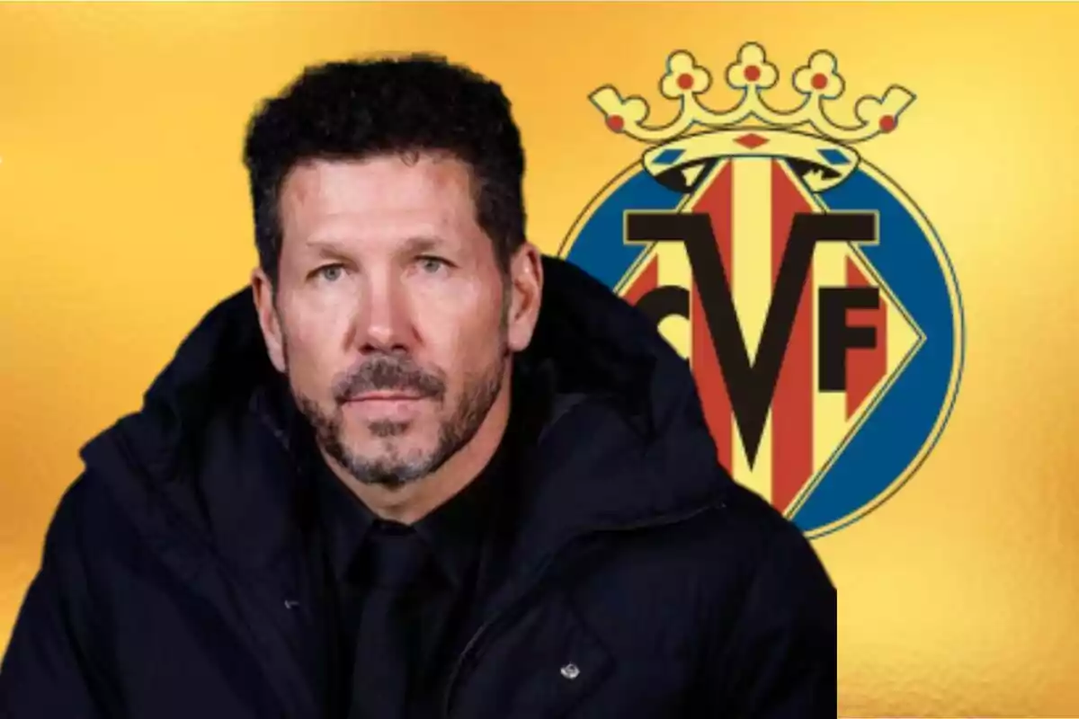 Hombre con barba y cabello corto vestido con abrigo oscuro frente al escudo del Villarreal sobre un fondo amarillo