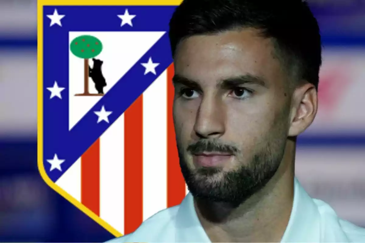 Un hombre con barba y cabello corto aparece en primer plano con el escudo del Atlético de Madrid de fondo.