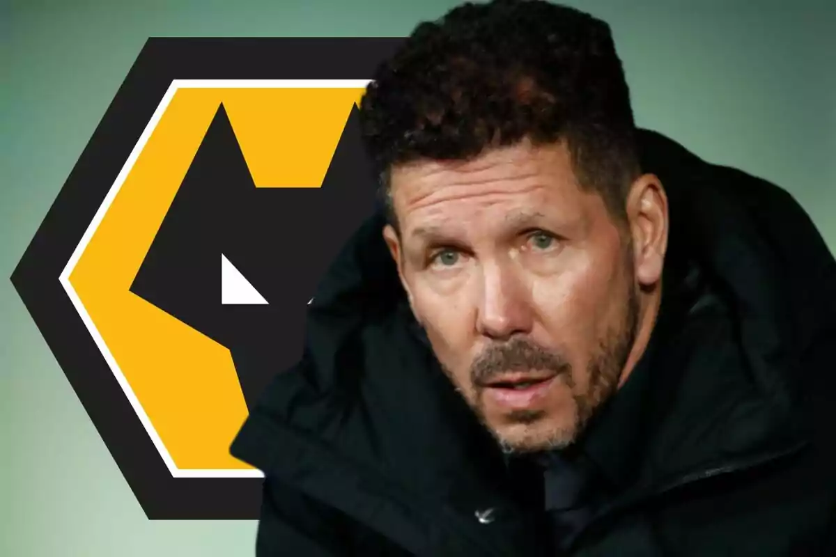 Hombre de cabello rizado y barba con chaqueta oscura frente al logo del club Wolverhampton Wanderers