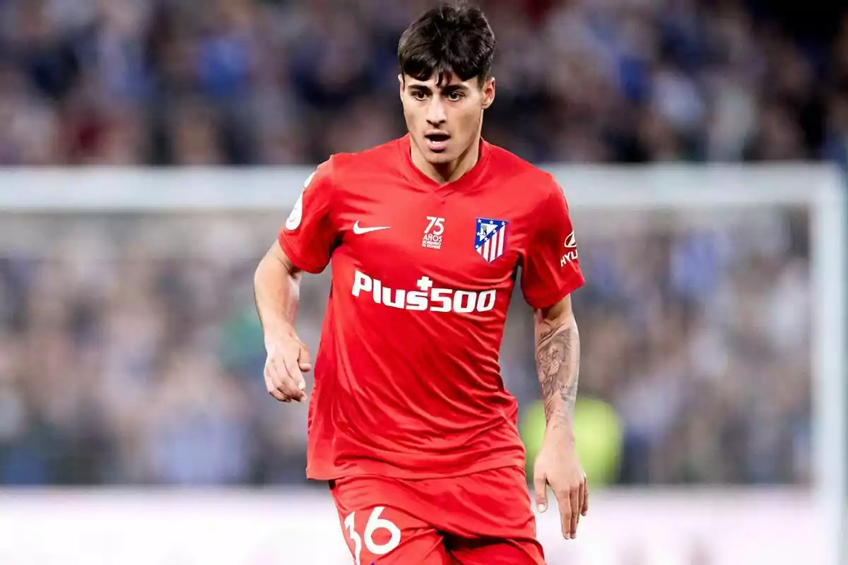Futbolista con uniforme rojo del Atlético de Madrid corriendo en el campo durante un partido Futbolista con uniforme rojo del Atlético de Madrid corriendo en el campo durante un partido