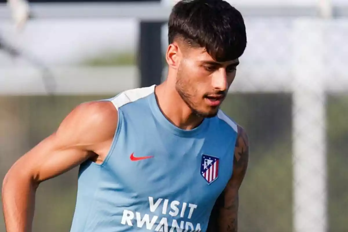 Jugador de fútbol con camiseta de entrenamiento azul del Atlético de Madrid durante una práctica al aire libre Jugador de fútbol con camiseta de entrenamiento azul del Atlético de Madrid durante una práctica al aire libre