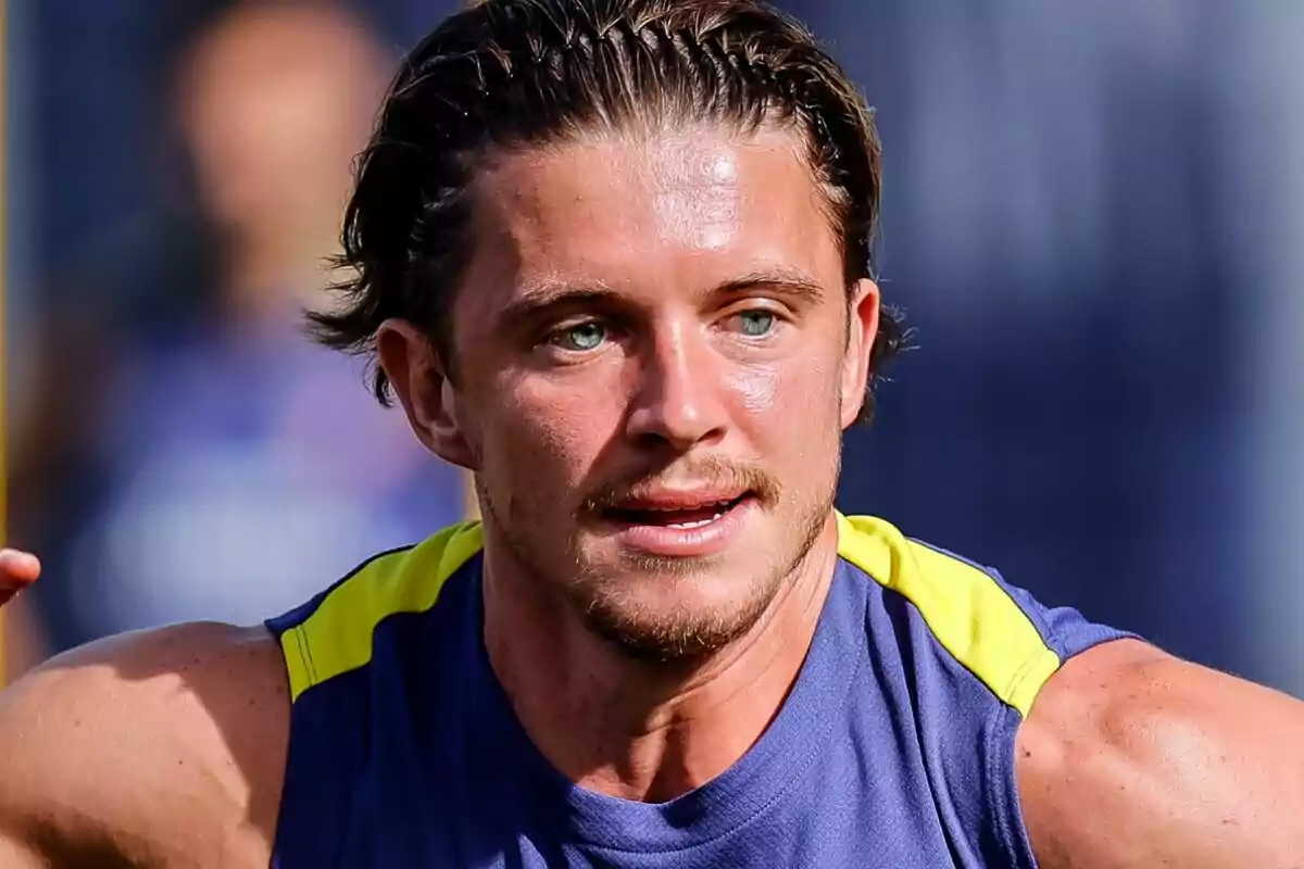 Hombre joven con camiseta deportiva azul y amarilla corriendo al aire libre