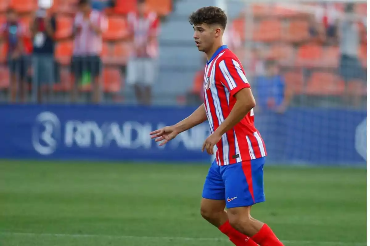 Jugador de fútbol con uniforme rojo y blanco a rayas y pantalones cortos azules en un campo de juego durante un partido Jugador de fútbol con uniforme rojo y blanco a rayas y pantalones cortos azules en un campo de juego durante un partido