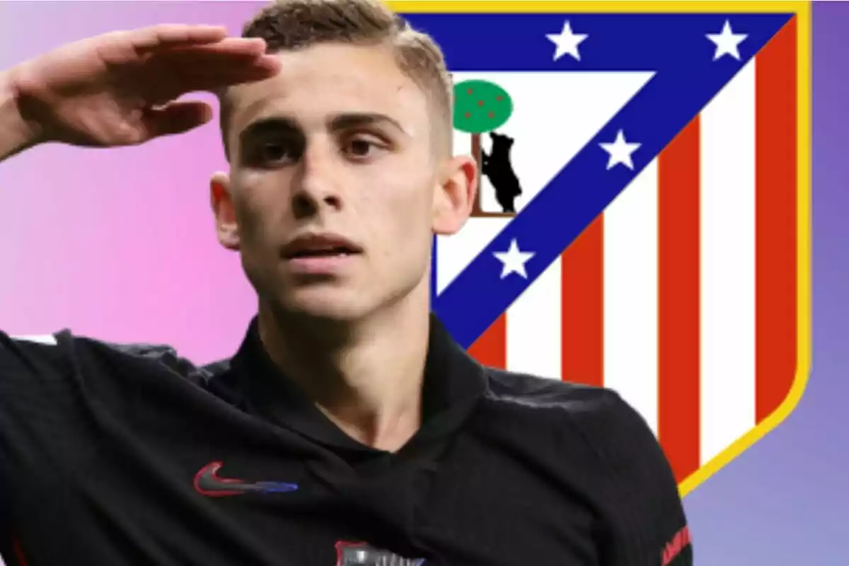 Futbolista con uniforme negro saludando frente al escudo del Atlético de Madrid