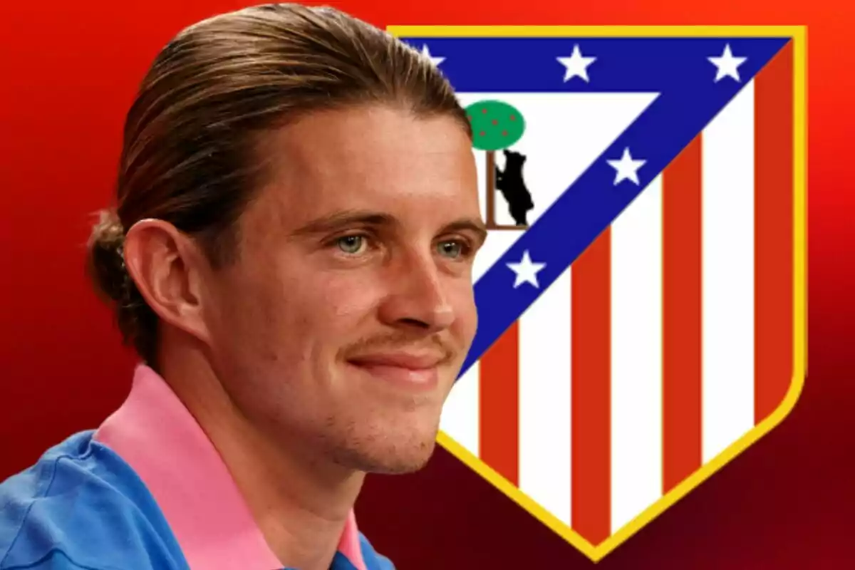 Un hombre sonriente con camisa azul y rosa aparece frente al escudo del Atlético de Madrid sobre un fondo rojo