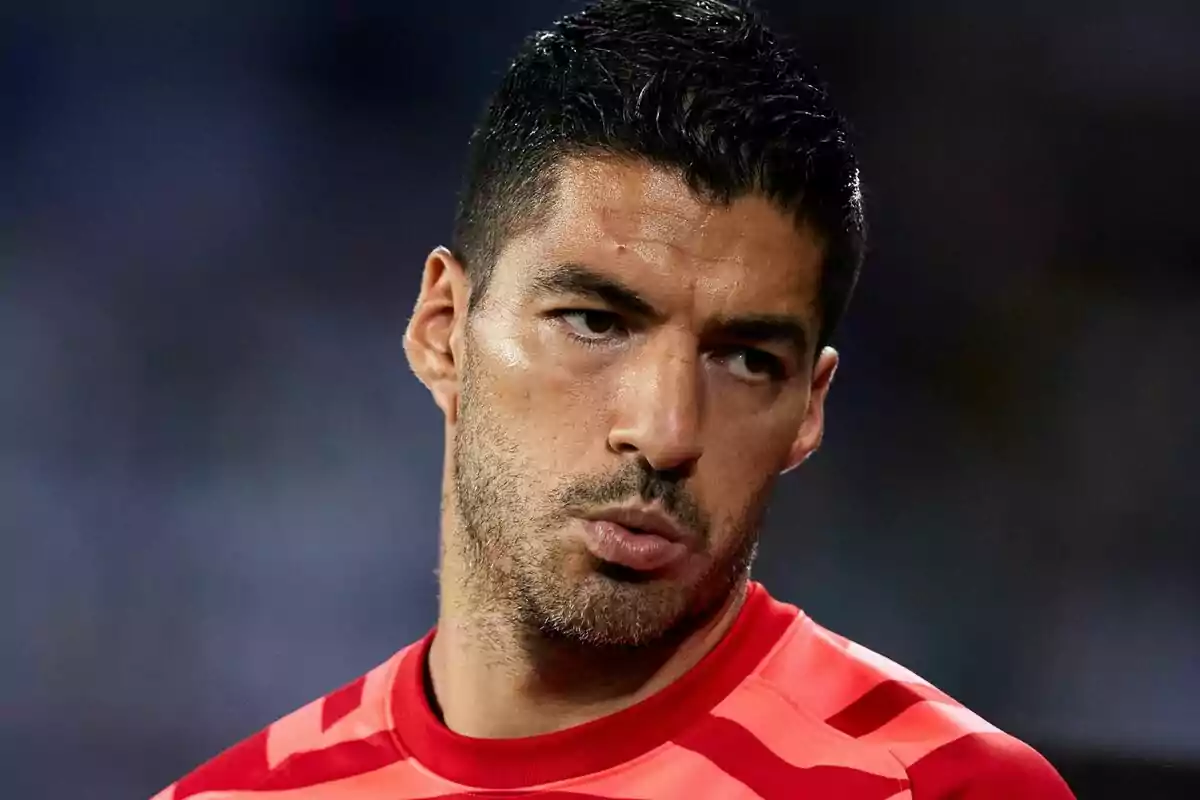 Hombre con camiseta deportiva roja mirando hacia un lado con expresión seria