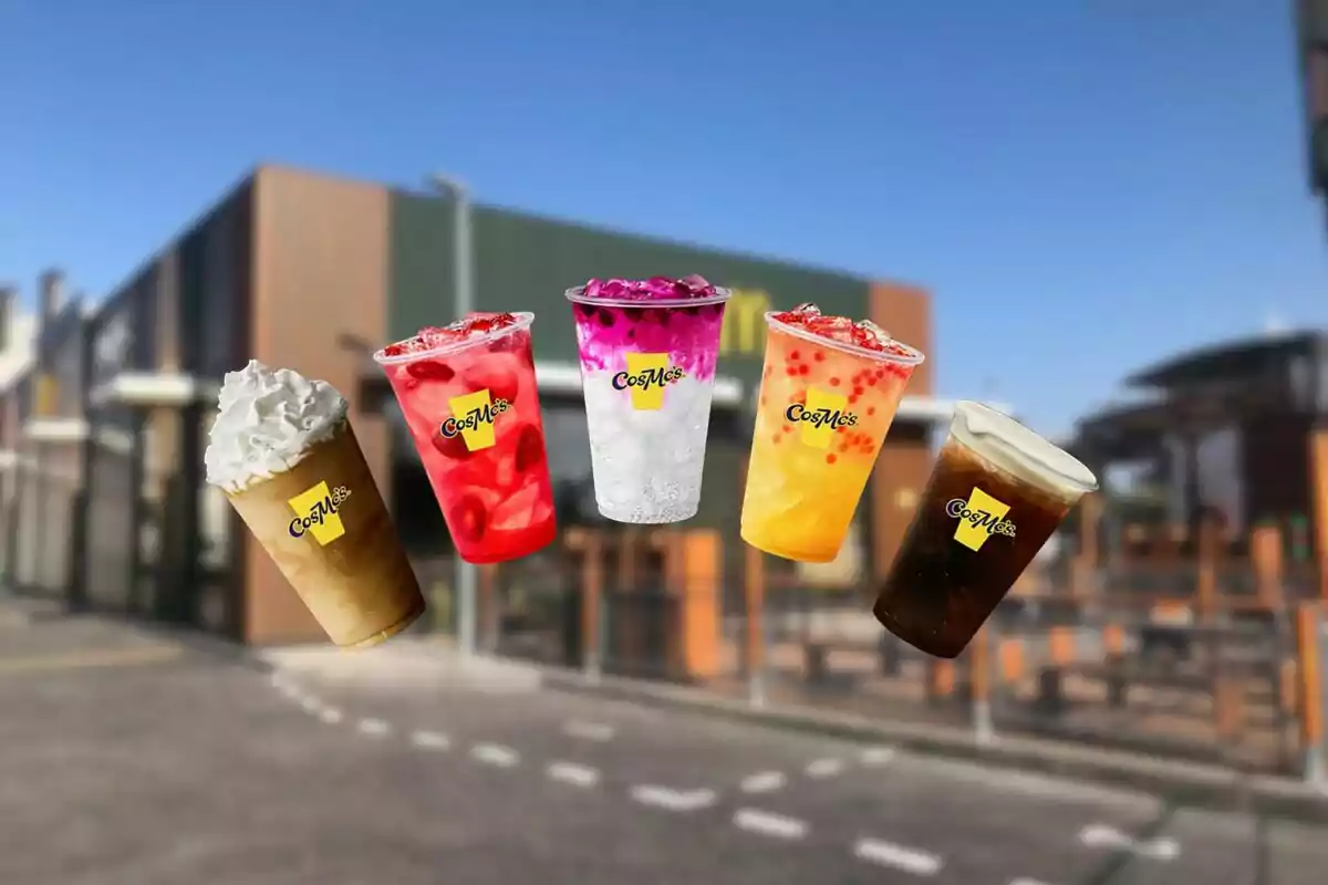 Five colorful drinks from the CosMc’s brand float in front of a modern building under a clear sky. Five colorful drinks from the CosMc’s brand float in front of a modern building under a clear sky.