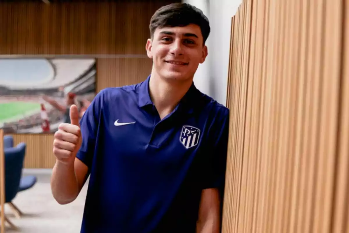 Joven con camiseta azul del Atlético de Madrid sonriendo y levantando el pulgar en señal de aprobación Joven con camiseta azul del Atlético de Madrid sonriendo y levantando el pulgar en señal de aprobación