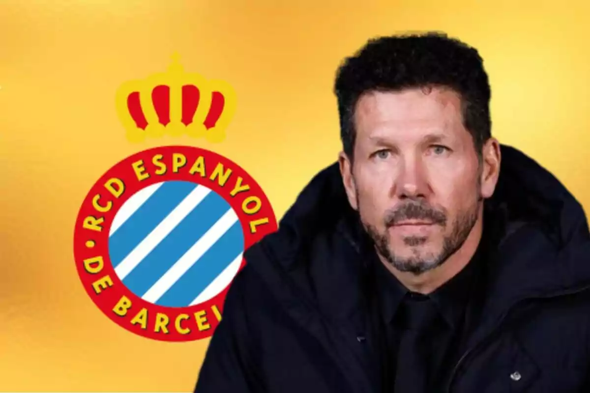 Un hombre con barba y cabello corto oscuro viste abrigo negro y está frente al escudo del RCD Espanyol sobre un fondo amarillo.
