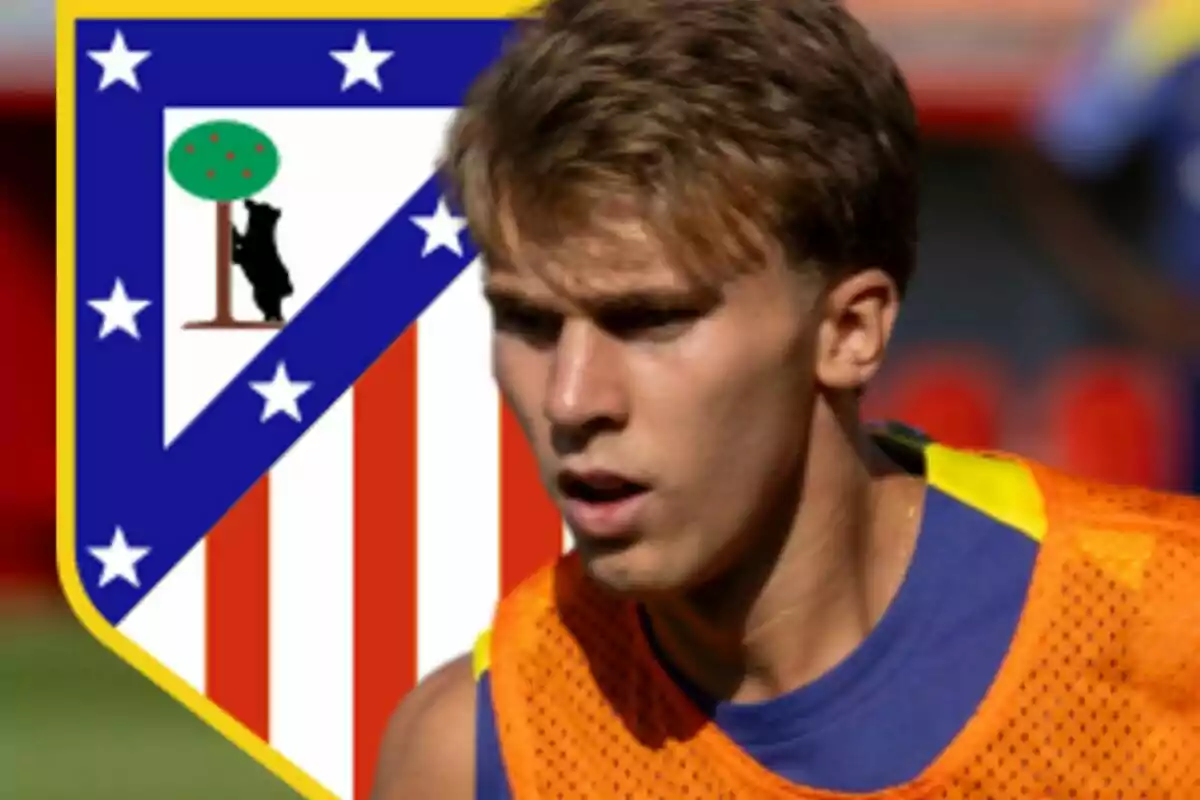 Joven futbolista con peto naranja frente al escudo del Atlético de Madrid