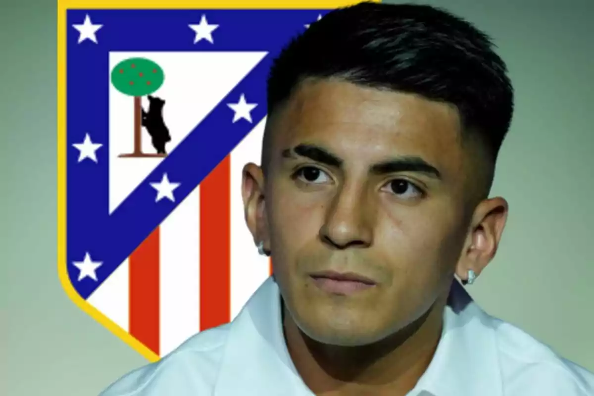 Joven con camisa blanca y aretes posando frente al escudo del Atlético de Madrid