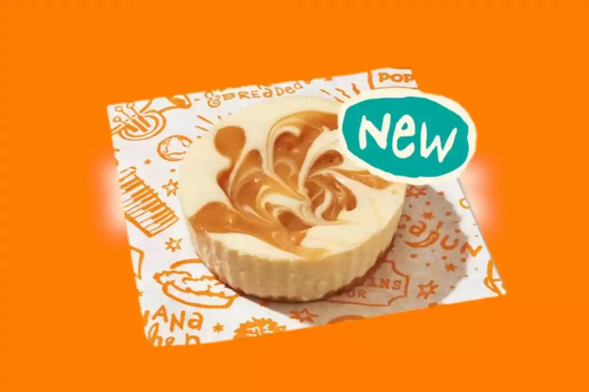 Round cheesecake-style dessert with caramel swirl on decorative paper and orange background Round cheesecake-style dessert with caramel swirl on decorative paper and orange background