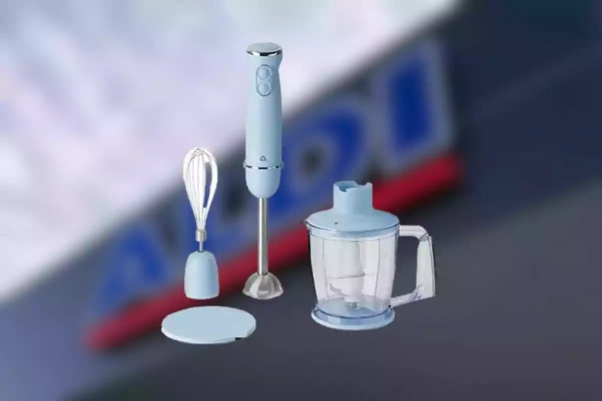 Batidora de mano con accesorios de color azul claro sobre un fondo desenfocado de un letrero de supermercado Batidora de mano con accesorios de color azul claro sobre un fondo desenfocado de un letrero de supermercado
