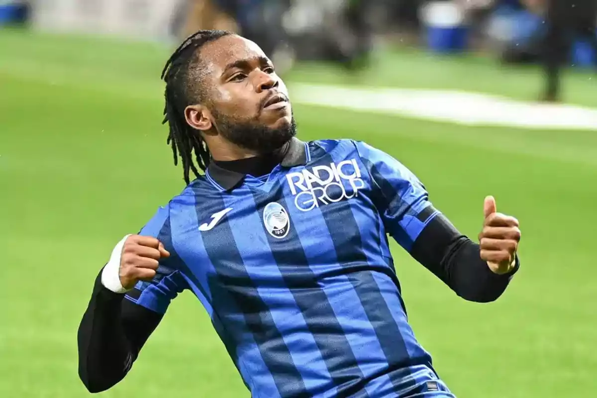 Jugador de fútbol celebrando en el campo con uniforme azul y negro.