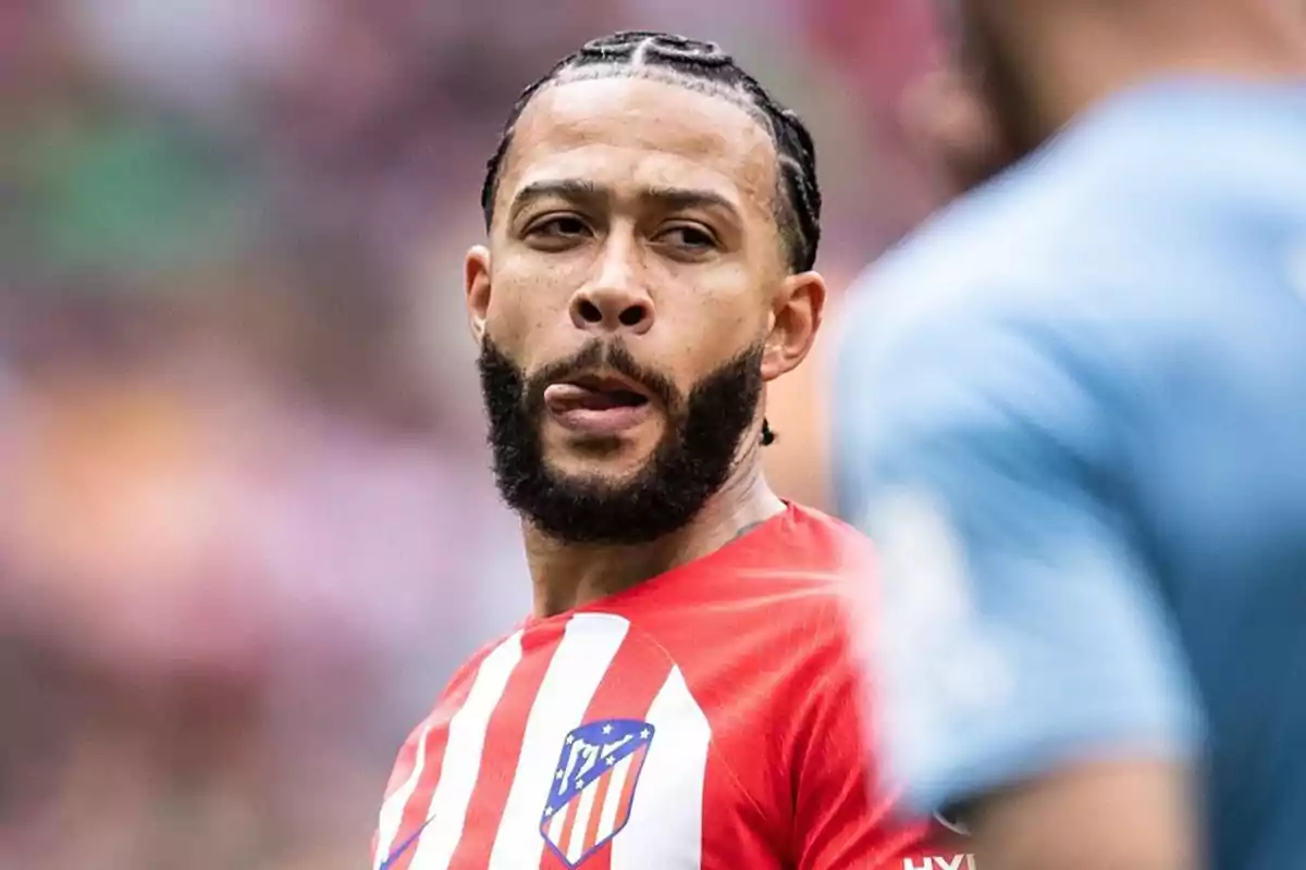 Jugador de fútbol con camiseta del Atlético de Madrid en el campo de juego.