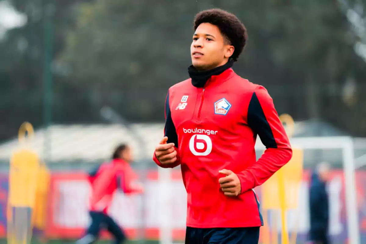 Un jugador de fútbol entrenando con el uniforme del equipo LOSC Lille en un campo al aire libre.