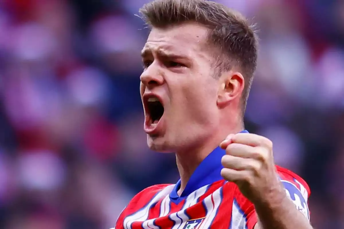 Un jugador de fútbol celebrando con entusiasmo mientras viste la camiseta del Atlético de Madrid.