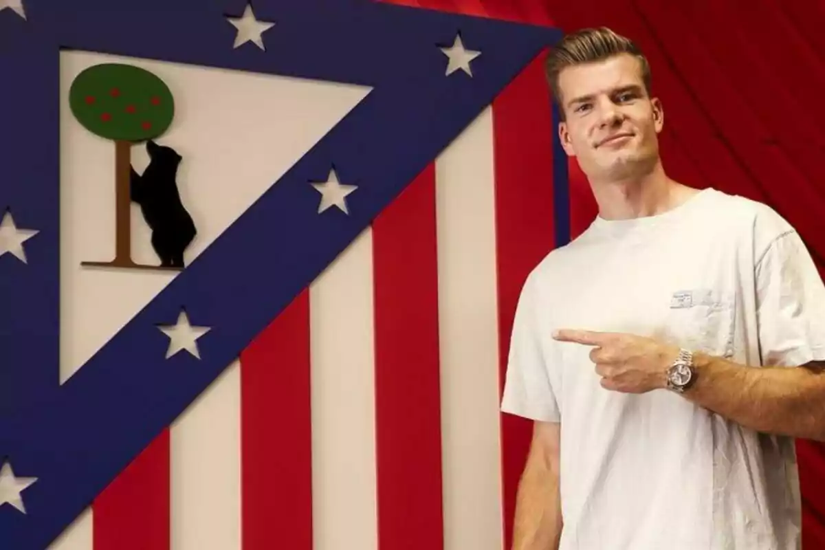 Un hombre con camiseta blanca señala el escudo del Atlético de Madrid.