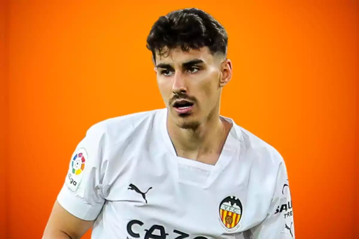 Un jugador de fútbol con camiseta blanca del Valencia CF y fondo naranja.