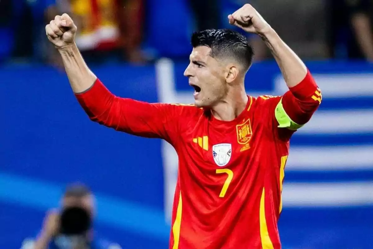 Jugador de fútbol con uniforme rojo celebrando con los brazos en alto.