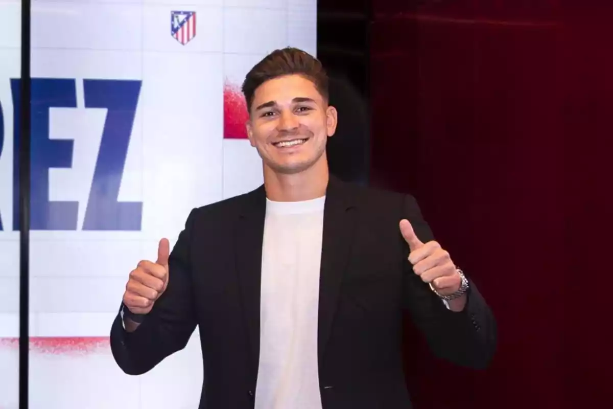 Un hombre sonriente con pulgares hacia arriba frente a un fondo con el logo del Atlético de Madrid.