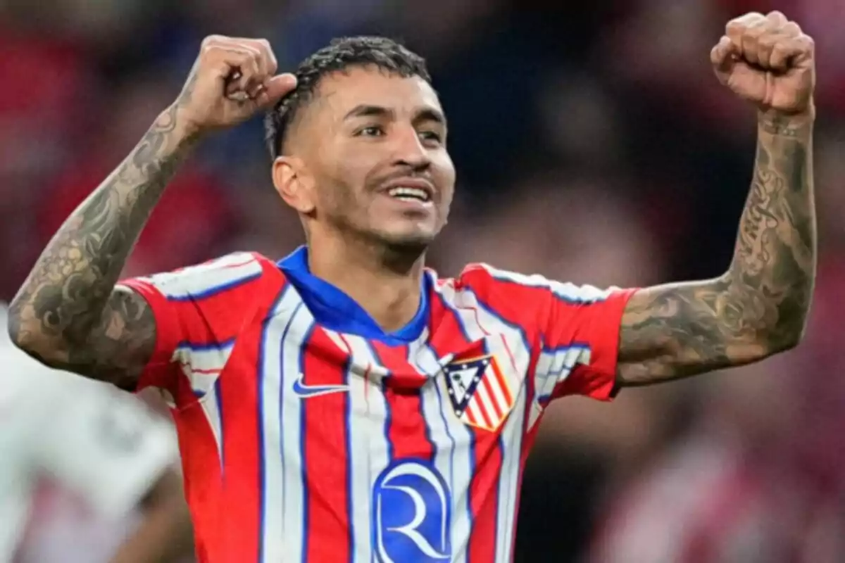 Jugador de fútbol celebrando con los brazos en alto mientras viste la camiseta del Atlético de Madrid.