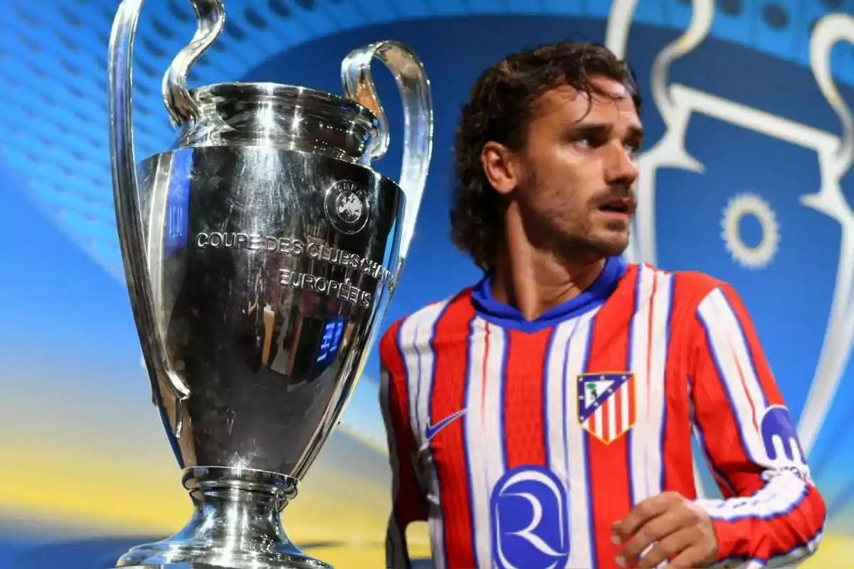 Un jugador de fútbol con la camiseta del Atlético de Madrid junto a un trofeo grande de plata.