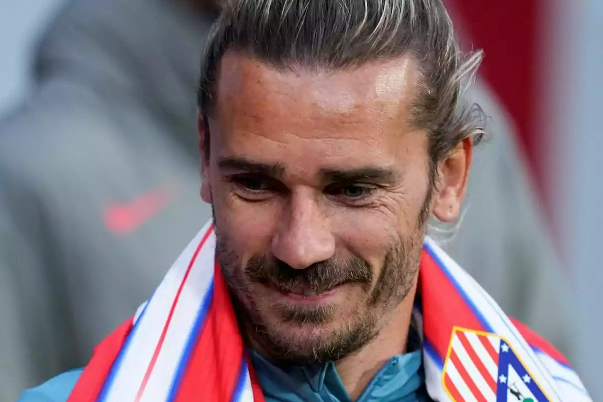 Hombre sonriente con bufanda del Atlético de Madrid sobre los hombros