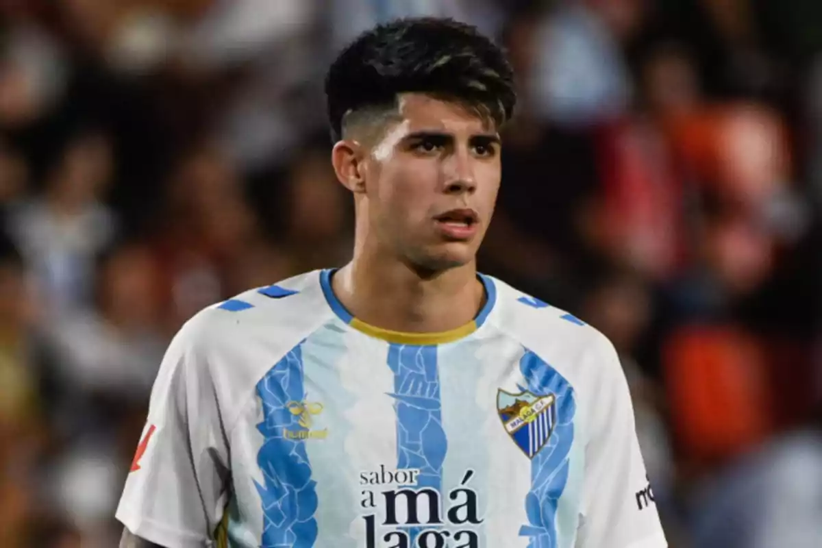 Un jugador de fútbol con la camiseta del Málaga CF en el campo.