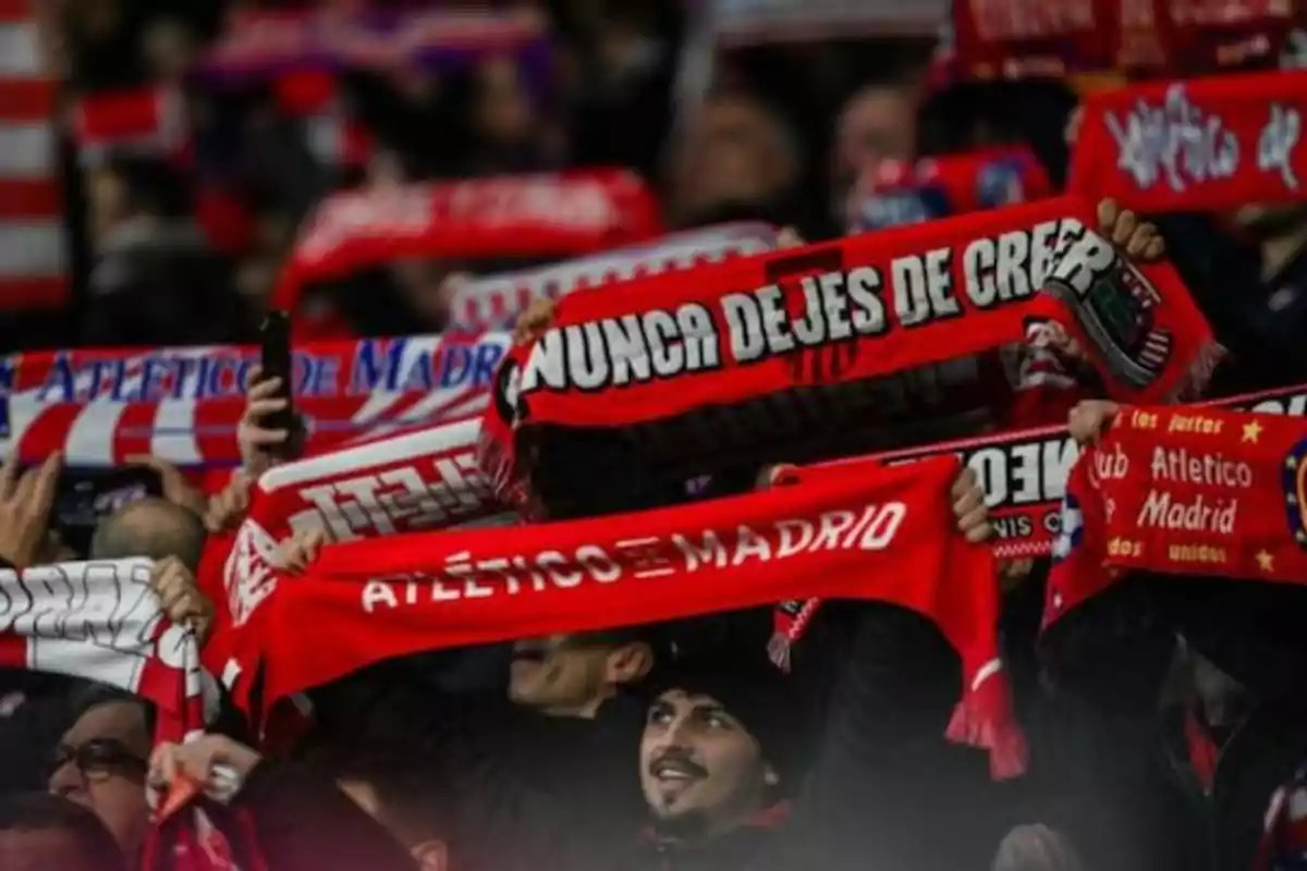 Atletico Madrid fans holding red and white scarves in a stadium. Atletico Madrid fans holding red and white scarves in a stadium.