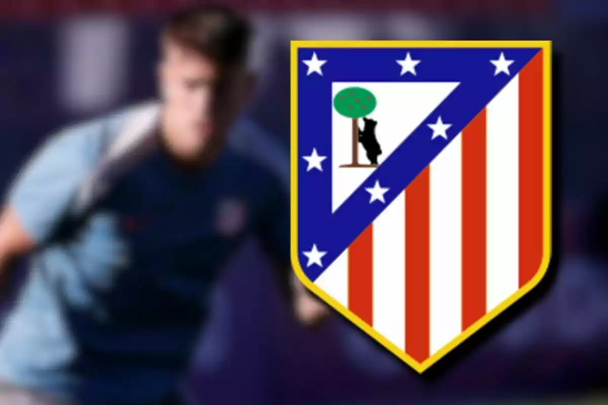 Escudo del Atlético de Madrid con una persona desenfocada de fondo.