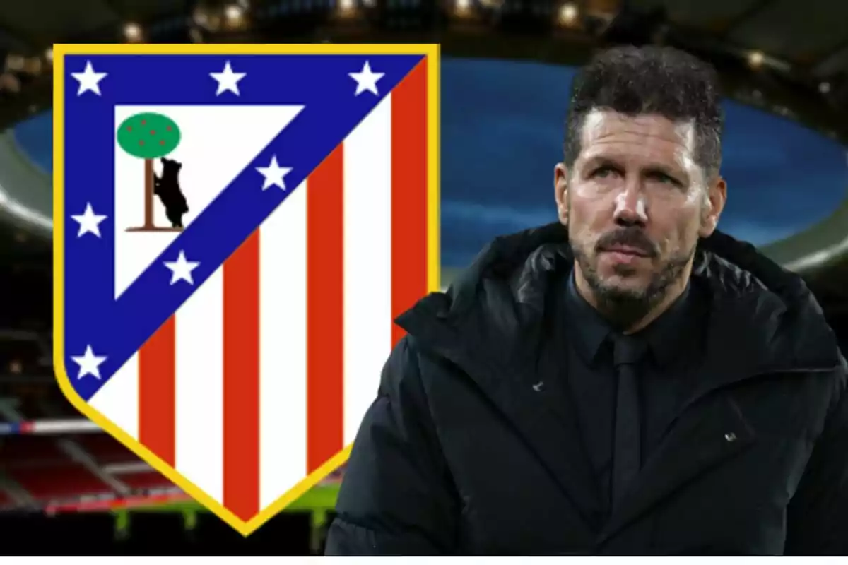 Man in black jacket in front of the Atlético de Madrid crest in a stadium.